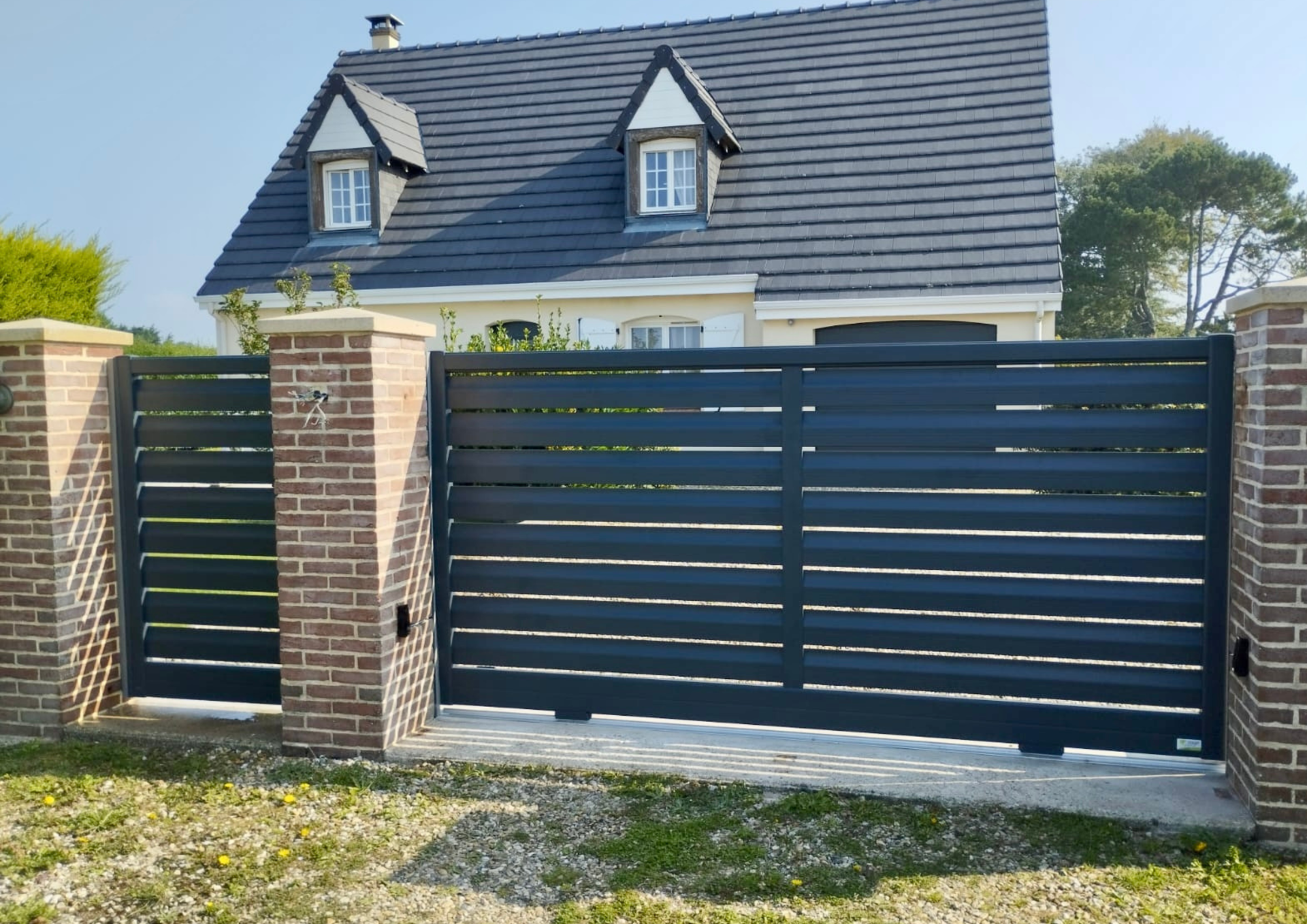 Portail bleu coulissant avec une maison derriére